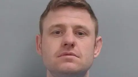 Mugshot of Liam Evans. He has very faint stubble and short fair hair.