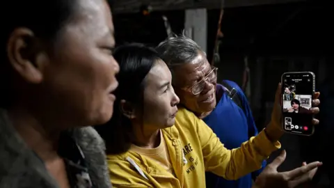 Getty Images Thai farm worker Watchara Sriaoun who was a hostage in Gaza, speaks via video call to his family and friends at his native home in Udon Thani on January 30, 2025, after his release by Hamas.