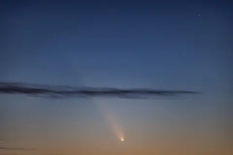 Martin Cohen Un cielo nocturno iluminado con un brillante haz de luz, con una nube oscura. 