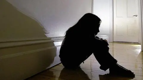A silhouette of a girl sitting on the floor. 