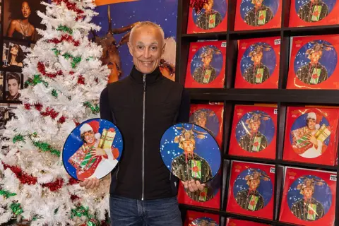 Getty Images Andrew Ridgeley from Wham holds up festive copies of Last Christmas