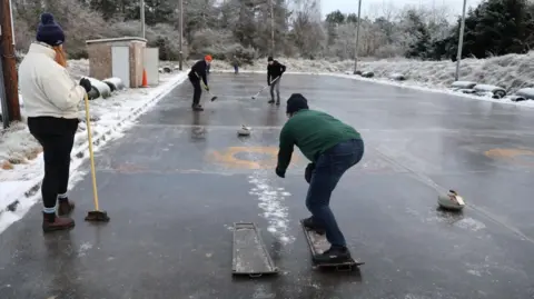 A group of curlers in action on an outdoor rink in Muir of Ord.