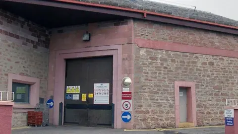 HMP Inverness - a red and brown brick building with a brown door 