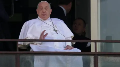 The Pope sits and waves from his hospital window