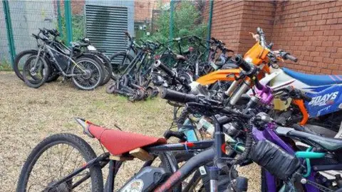 Lancashire Police Rows of 40 seized bikes are seen lined around a yard next to a redbrick building.