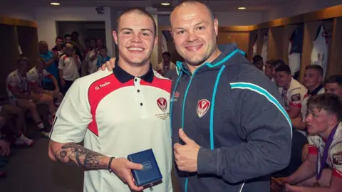 A young Jonah Cunningham stands with his dad Kieron in the changing room at St Helens