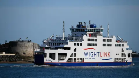 Getty Images A blue and white ferry with the Wightlink logo on it, sailing out of a harbour on a bright sunny day.