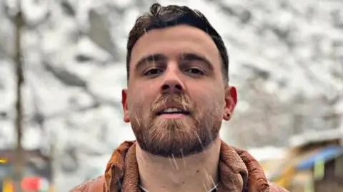 Hengaw Organization for Human Rights An undated image of Erfan Soltani. He looks at the camera with a slight smile as rain or snow appears to fall. 