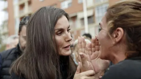 EPA Mud on the queen's face, holding the woman's hands as she speaks to her