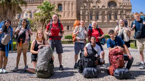 All 10 Race Across the World contestants, pictured outside Palermo Cathedral, lined up and ready to go with their backpacks on