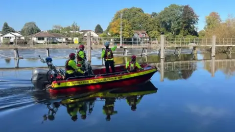 BBC Fire and Rescue officers on a boat on the River Thames at Sunbury as part of a rescue operation 