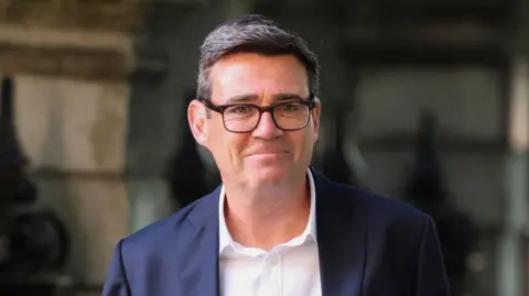 Andy Burnham wearing a dark suit and a white shirt