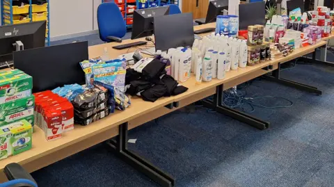 Cambridgeshire Police Some of the suspected stolen goods have been set out on a table by police. This includes Lint chocolate, coffee, Galaxy, Snickers and celebrations. 