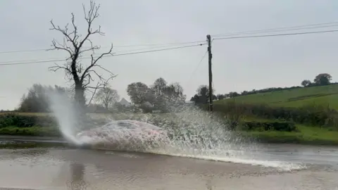 PA Media A car driving through a flooded road in Cookstown, Co Tyrone