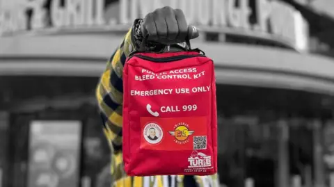 Wingman Mentors Person holding up bleed kit