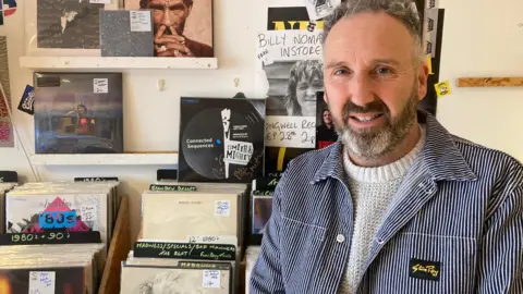 Iain Aitchison standing in front of a collection of vinyls