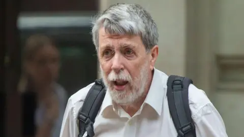 Alamy  Gareth Jenkins, (man with white beard, wearing white shirt and  carrying a rucksack) former engineer at Fujitsu Services Ltd, arrives at Post Office Horizon IT Inquiry Public, 27 June 2024.