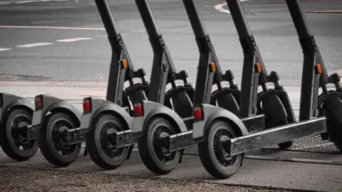 A row of parked e-scooters in a town centre