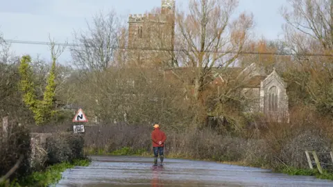 A man looks at floodwater in Harbridge, Hampshire.