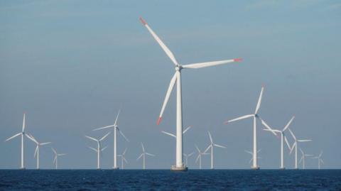 Several white turbines in the sea