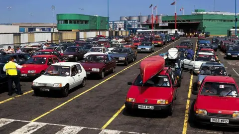 Portsmouth International Port Cars in the port car park, possibly in the 90s. One has a canoe on its roof. 
