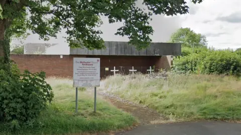 Google A derelict building with three white crosses outside and a sign at the front that says "The Methodist Church, Fordhouses". 