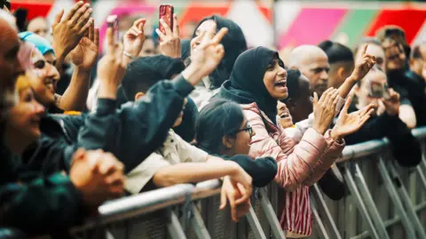 Glasgow Life Cheering crowd members at the barrier in front of the stage where acts at the festival perform