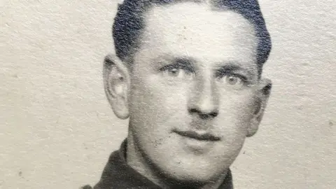 A black and white studio photo of George Whalebelly. He has short hair and his Army tunic collar can just be seen.
