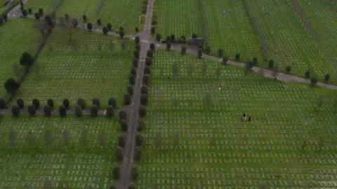 Getty Images An aerial image of hundreds of graves in neat rows with paths intersecting the grassy areas. 