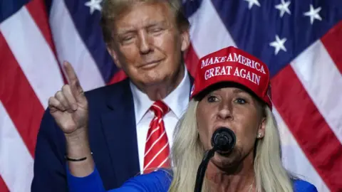 AFP via Getty Images A representante dos EUA, Marjorie Taylor Green (R), fala com o ex-presidente dos EUA e candidato presidencial de 2024, Donald Trump, em um evento de campanha em Roma, Geórgia, em 9 de março de 2024.