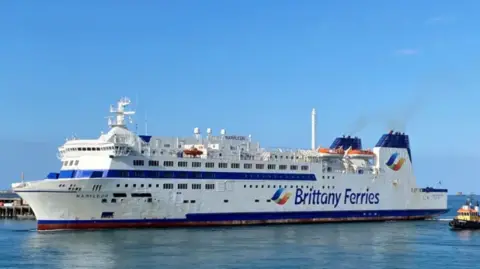 A white boat with the words Brittany Ferries arriving in St Peter Port Harbour. 