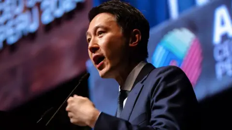 Getty Images Shou Zi Chew wearing a sharp suit with short hair speaking at an event.