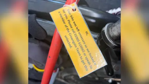 Bike Worcester A close up of a laminated card which reads: "Hi, Your bike was left unsecure so we locked it for you. Please call 01905 610065 or speak to a member of the Crowngate Team to get this unlocked."
