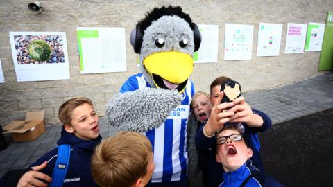 Brighton and Hove Albion mascot taking selfie with supporters