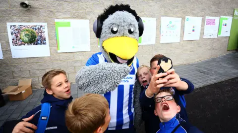 Getty Images Brighton and Hove Albion mascot taking selfie with supporters
