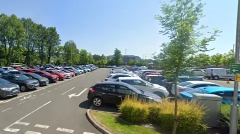 Google A car park on a sunny day, with dozens of cars parked there