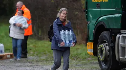 A woman carrying a six pack of water