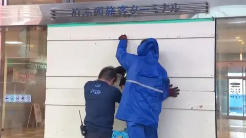 Two men board up a building