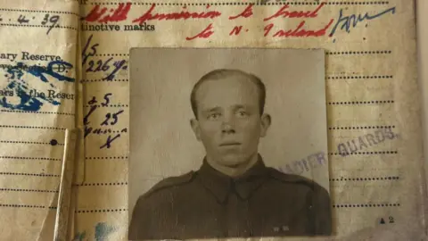 A brown and white image of Mr Irwin taken on top of a notebook with different coloured writing in it. He is wearing his military uniform in the picture and has short hair. 