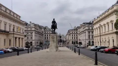 View down Waterloo Place with an equestrian statue centred between historic buildings.