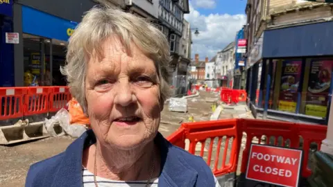 Carol Powell standing near barriers