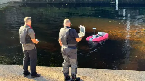 NRW workers calibrating measurements at a river monitoring station