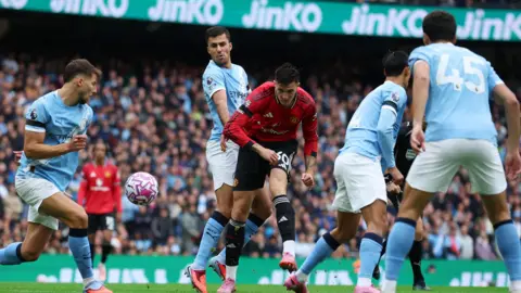 Reuters Manchester City's Ruben Dias in action with Manchester United's Benjamin Sesko with several other Manchester City players in view