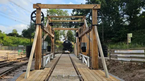 Supplied Train track and wooden archway with train in background