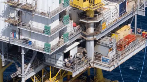 A group of people stands on an oil platform 