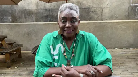 Allyson Williams sits at an outdoor table in west London while discussing Notting Hill Carnival ahead of its 60th anniversary.