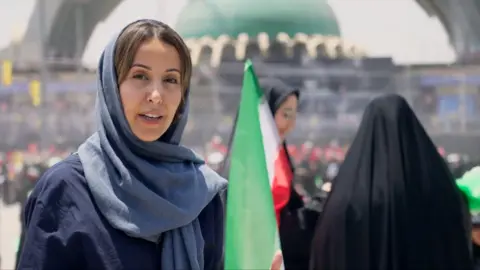 Nawal wears a lose blue hijab and abayah as she reports from the Grand Mosalla in Tehran