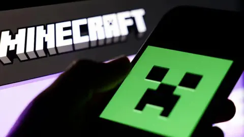 Getty Images The Minecraft website displayed on a laptop screen and Minecraft logo displayed on a mobile phone screen