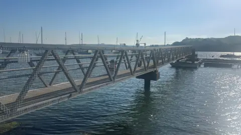 The pontoon stretching across the blue river with sunshine sparkling on the water