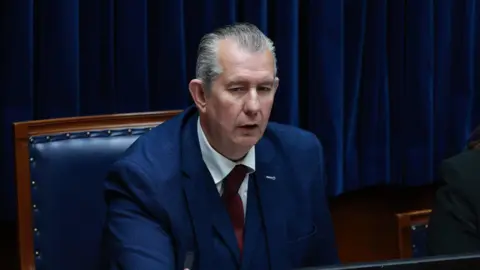 PA Media Stormont speaker Edwin Poots in the chamber wearing a blue suit with red tie.